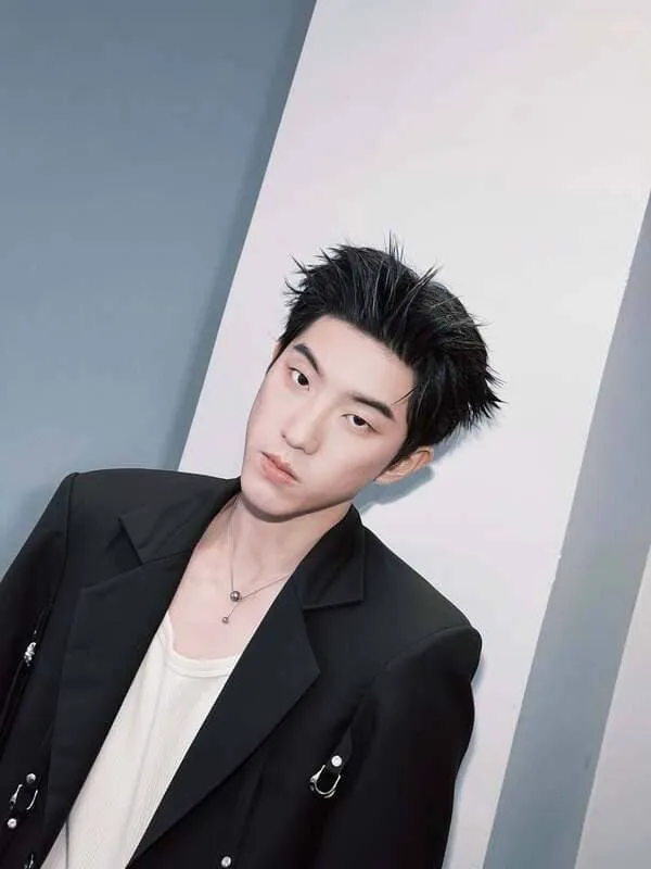 Ken Kanthee Limpitkranon mặc blazer đen đứng tựa tường