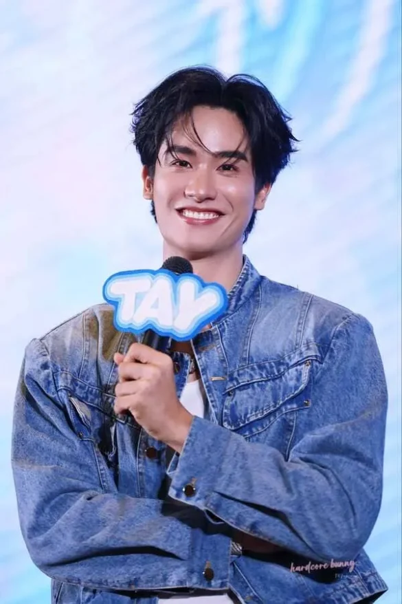 Tay Tawan Vihokratana tiểu sử cười rạng rỡ cầm bảng tên TAY