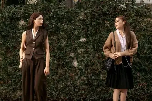 by-your-side-the-series-hinh-anh-6 By Your Side hai nữ chính mặc vest công sở đứng đối diện nhau trò chuyện trước hàng rào cây xanh