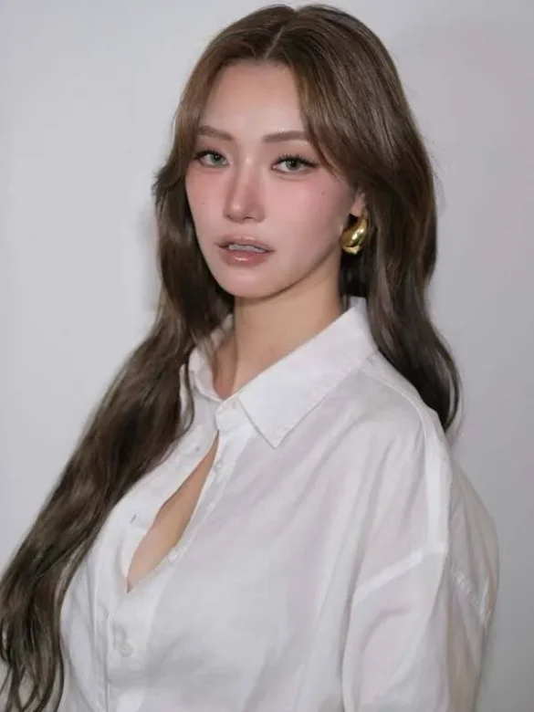 Ảnh JingJing Yu diện sơ mi trắng phông nền xám, khuyên tai vàng bản dày