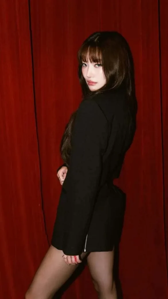Ảnh JingJing Yu ngoái đầu nhìn lại trước rèm nhung đỏ, blazer đen dáng ngắn