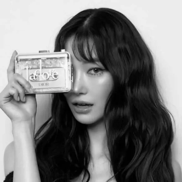 Ảnh JingJing Yu trắng đen che một bên mắt bằng chiếc clutch Dior