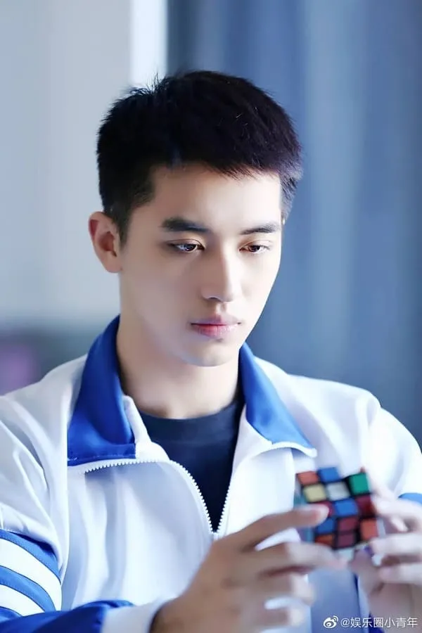 Bạch Lạc Nhân xoay khối rubik trong tay với ánh mắt chăm chú nhìn xuống